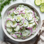 Greek Yogurt Cucumber Salad 2 Greek yogurt cucumber salad in a white bowl with dill and red onion on a marble table