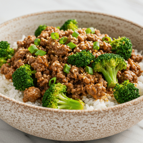Healthy Beef and Broccoli Stir Fry That Supports Clean Eating Goals 1 A close-up of a healthy beef and broccoli stir fry in a rustic speckled bowl, with the saucy ground beef and broccoli served over a bed of white rice.