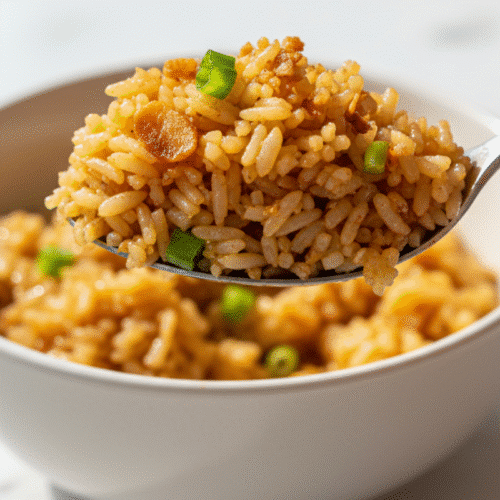 Garlic Fried Rice Recipe for Crispy, Easy Comfort Food 1 A close-up of a spoonful of the best garlic fried rice recipe, showing glistening grains and crispy garlic.