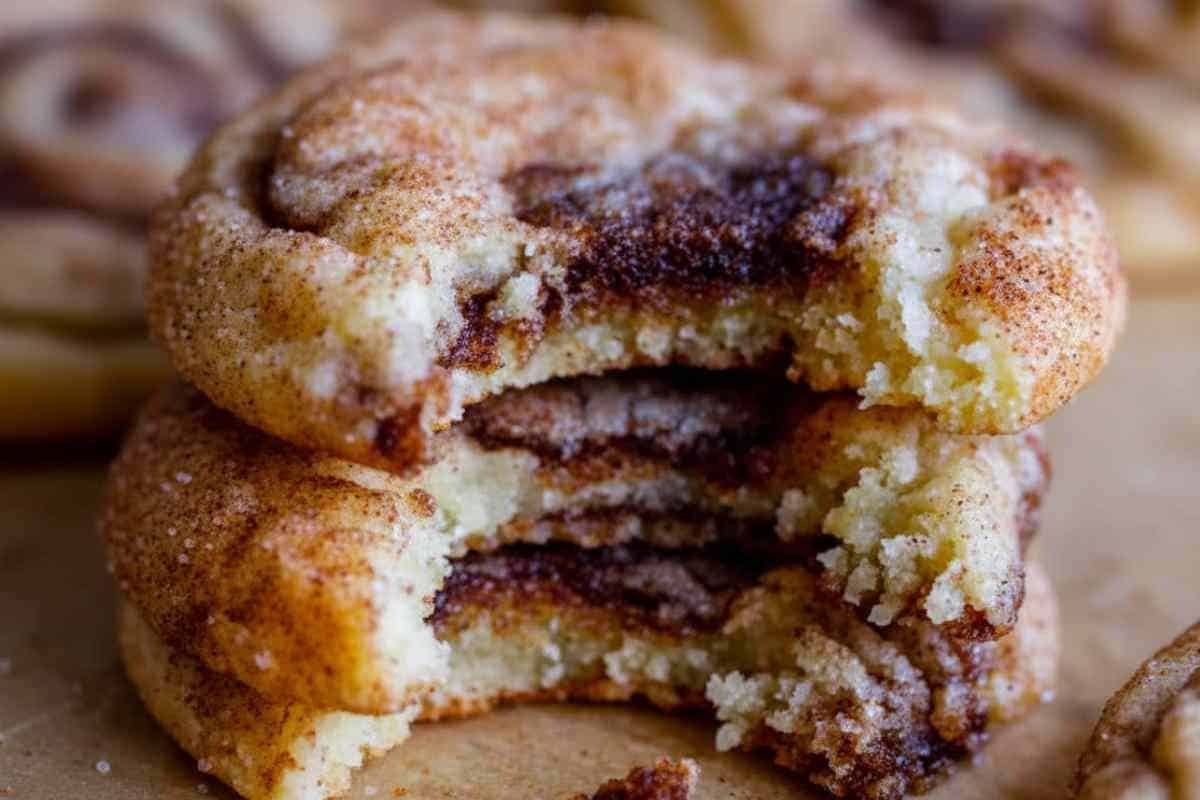 cinnamon-roll-cookies (1) Stacked cinnamon roll cookies with bite taken out showing soft interior texture and cinnamon swirl layers throughout cookie