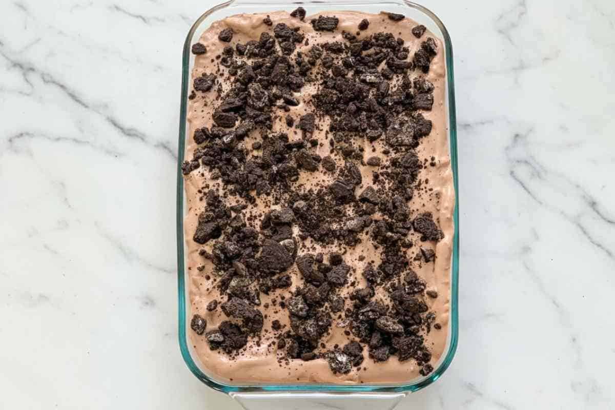 easy dirt cake recipe in glass baking dish with crushed oreos on top