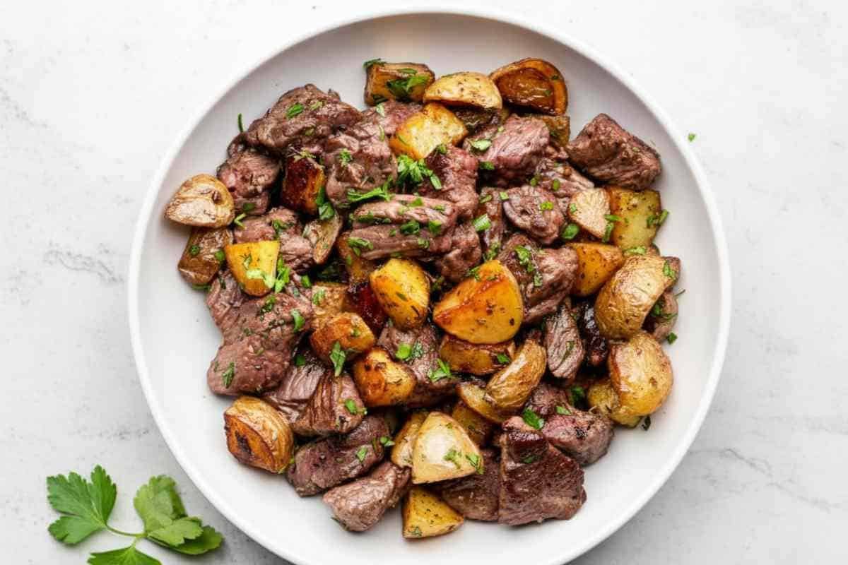 plated-garlic-butter-steak-bites-potatoes. Plated serving of garlic butter steak bites and potatoes ready to eat