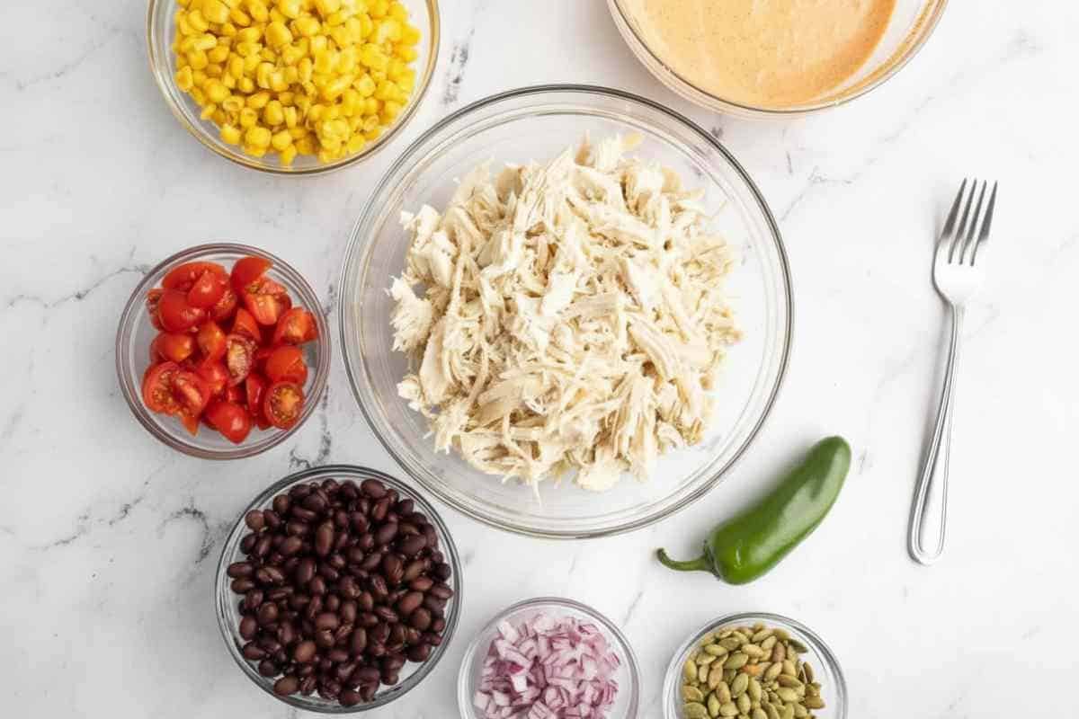 ingredients for southwest chicken salad including chicken beans corn jalapeños and lime
